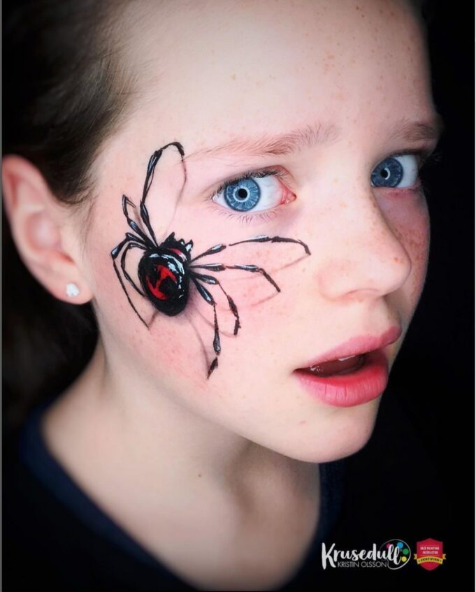 frightent child with a spider painted on its face