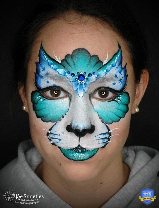 girl with a completed blue kitty cat face paint with her eyes open