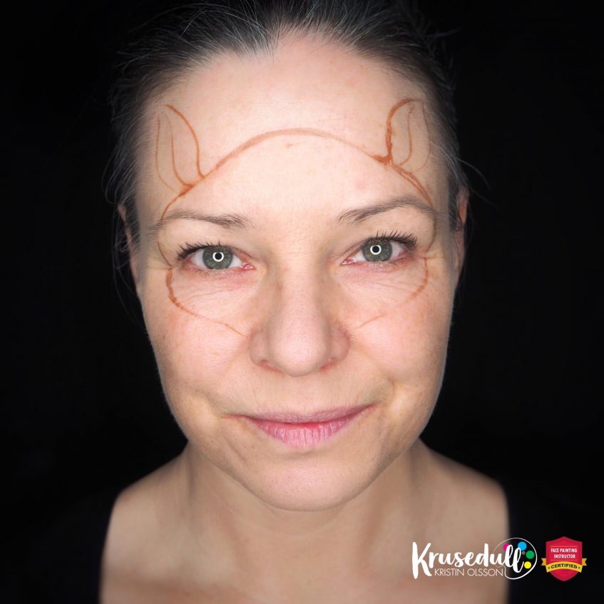 woman looking at the camera with a conture of a reindeer painted on her face