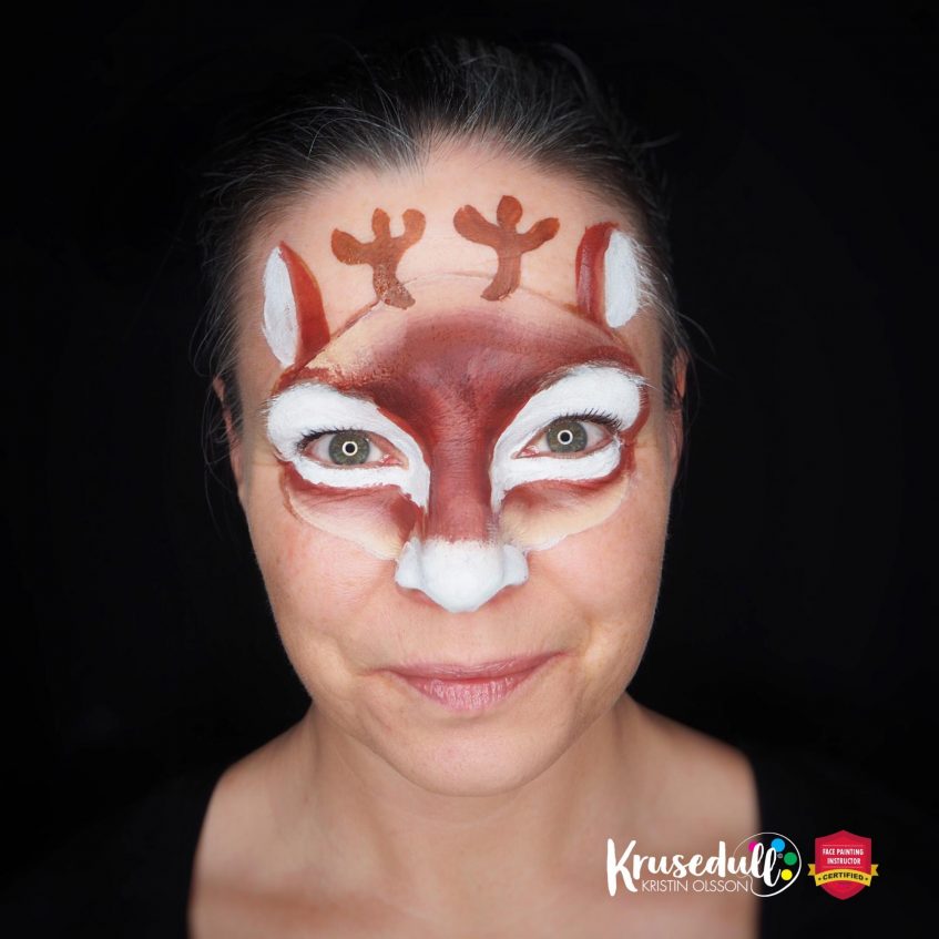 woman looking at the camera with a unfinished reindeer face paint