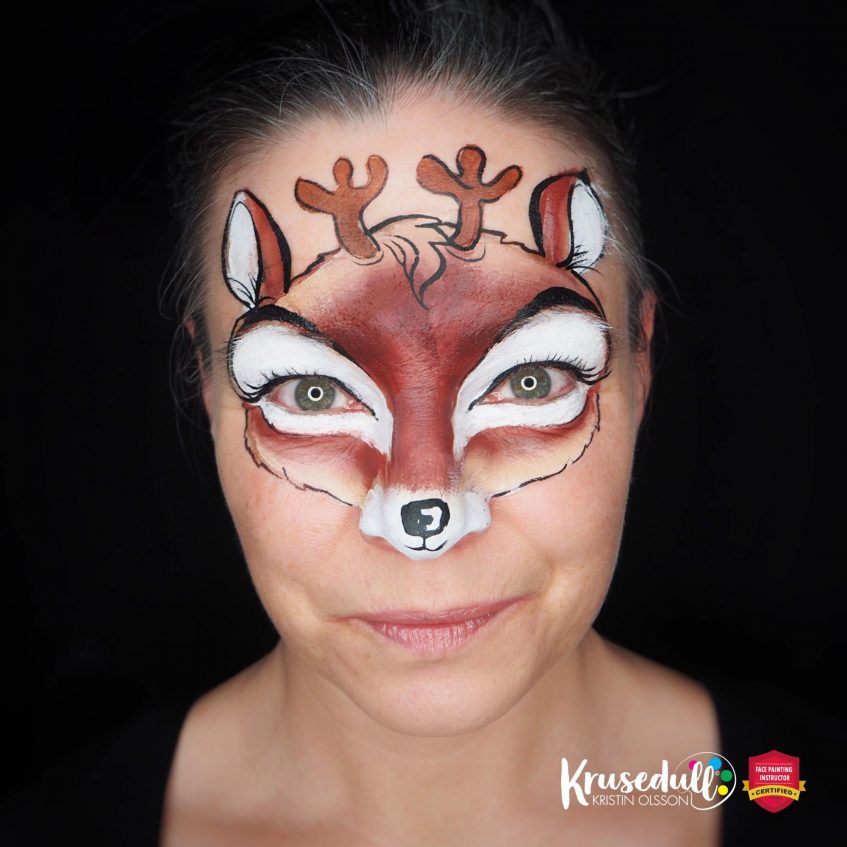 woman looking at the camera with a shaded brown and white reindeer face paint