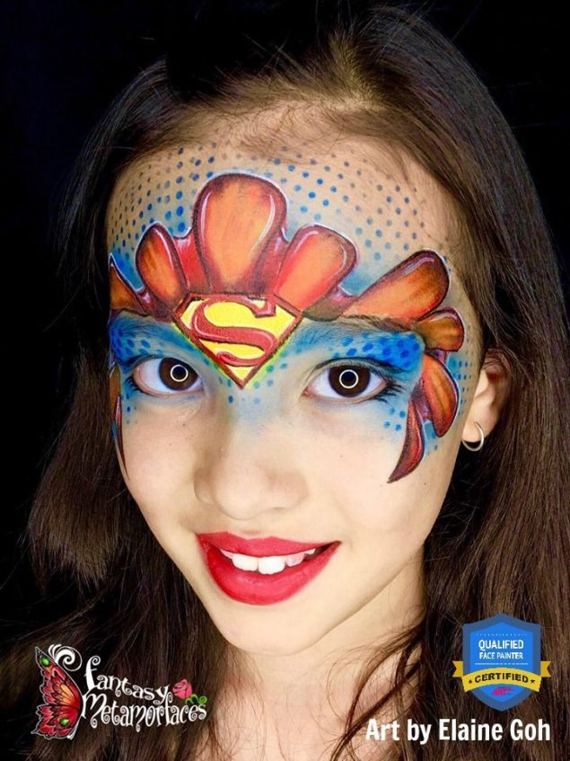 a girl looking at the camera with a superman face paint on her forehead