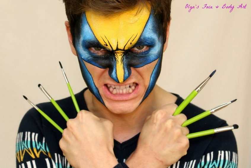a man with a wolverine face paint design holding brushes like his blades