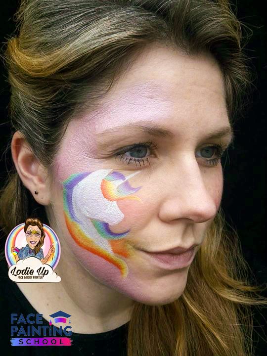 a woman with a base of a white unicorn face paint with rainbow mane