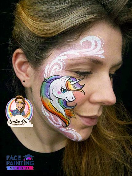 a woman with a almost completed unicorn face paint design